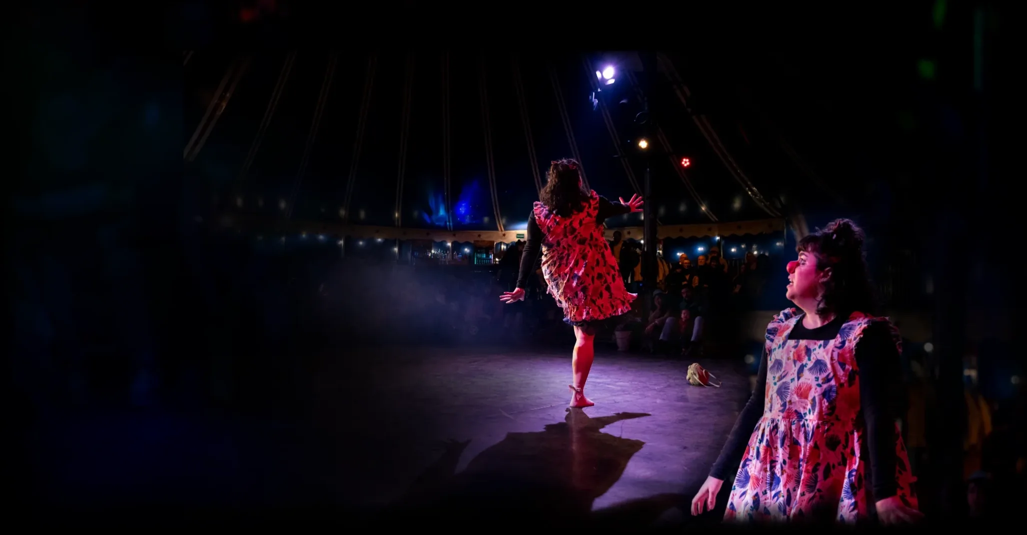 Clowns performing on stage in a circus tent
